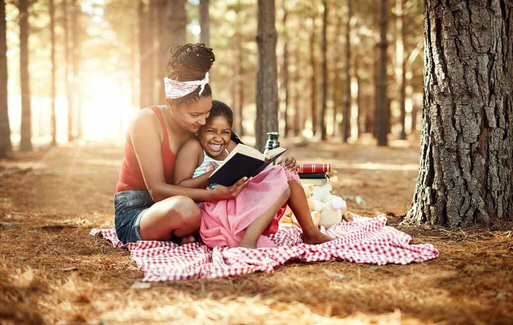 A woman reading to a girl on the ground.