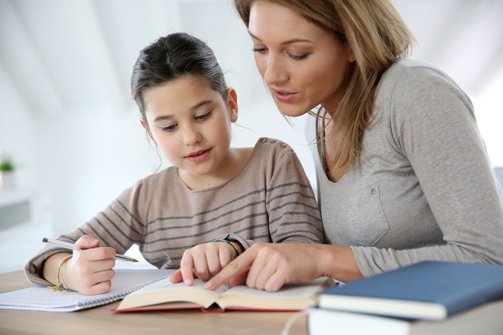 A woman helping a girl with her homework.