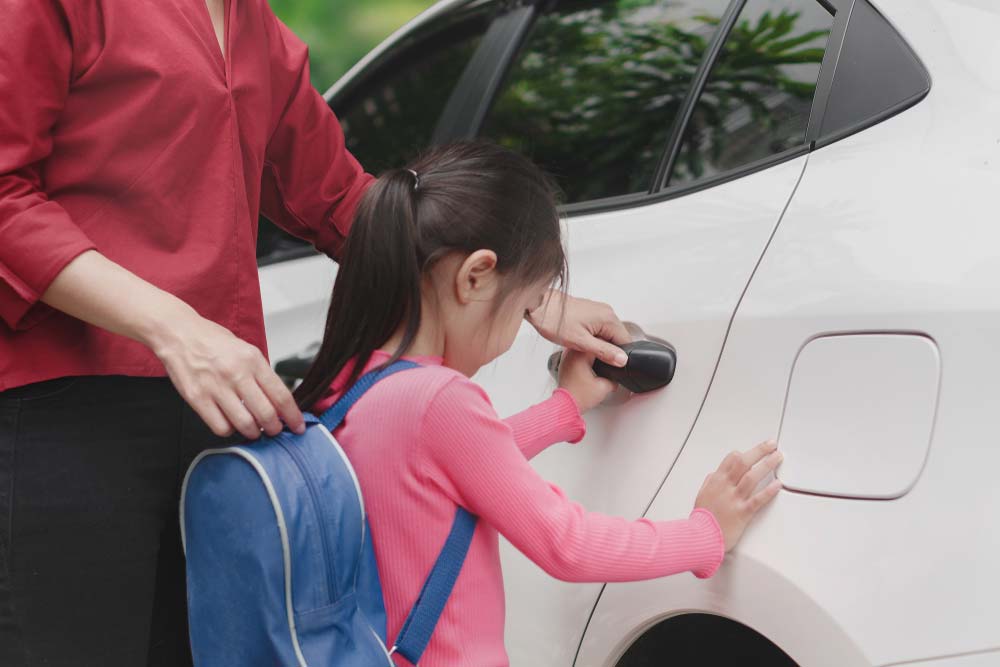 A girl wearing a backpack getting inside a car.