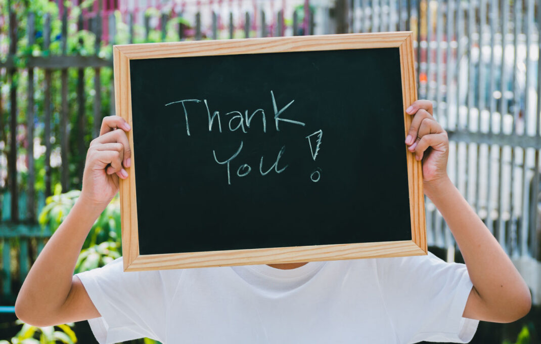 A child holding up a sign that says thank you.