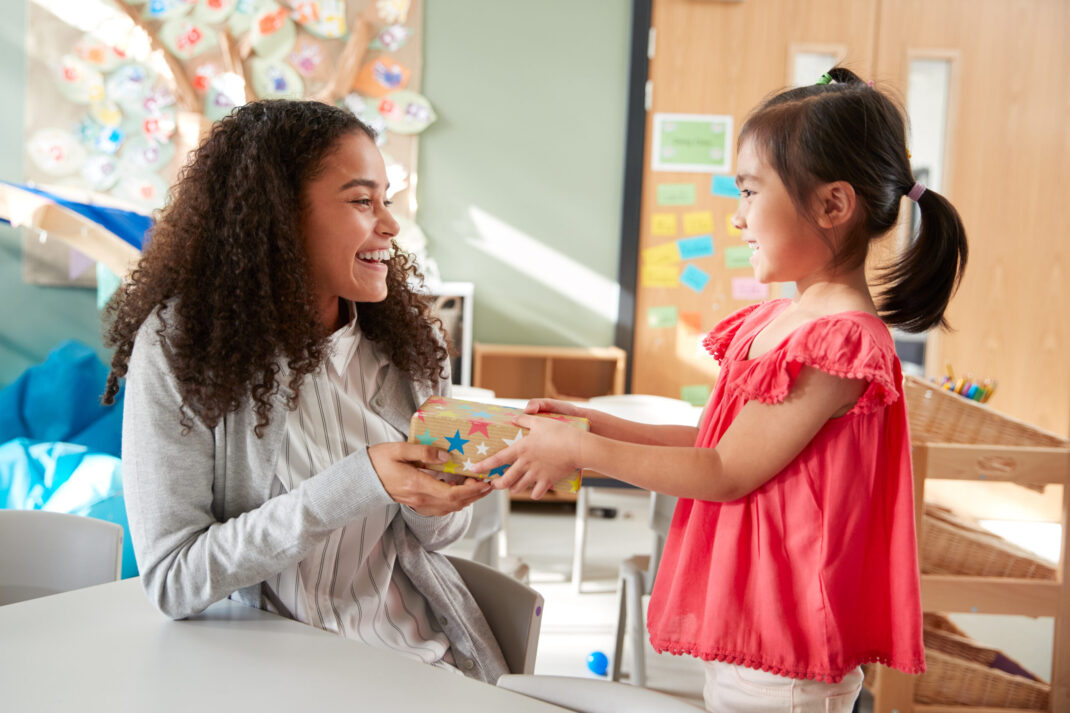 A girl handing a child a wrapped gift.