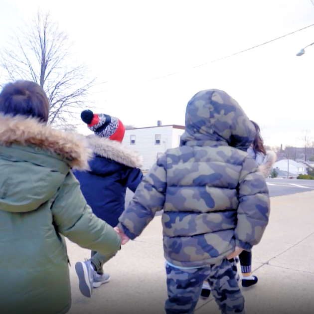 Two children walking down the street holding hands.