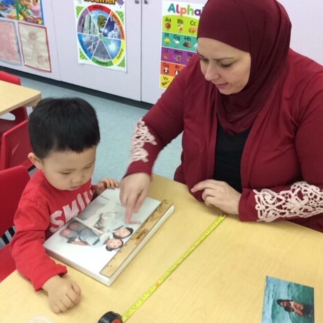 An instructor pointing to a photo beside a little boy.